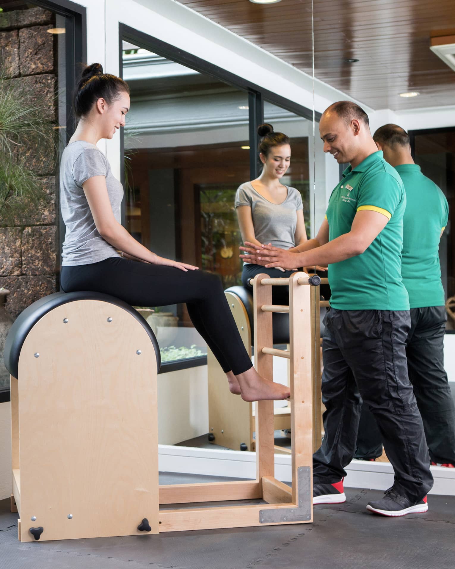 Four Seasons trainer assists woman balancing on pilates beam in Fitness Centre