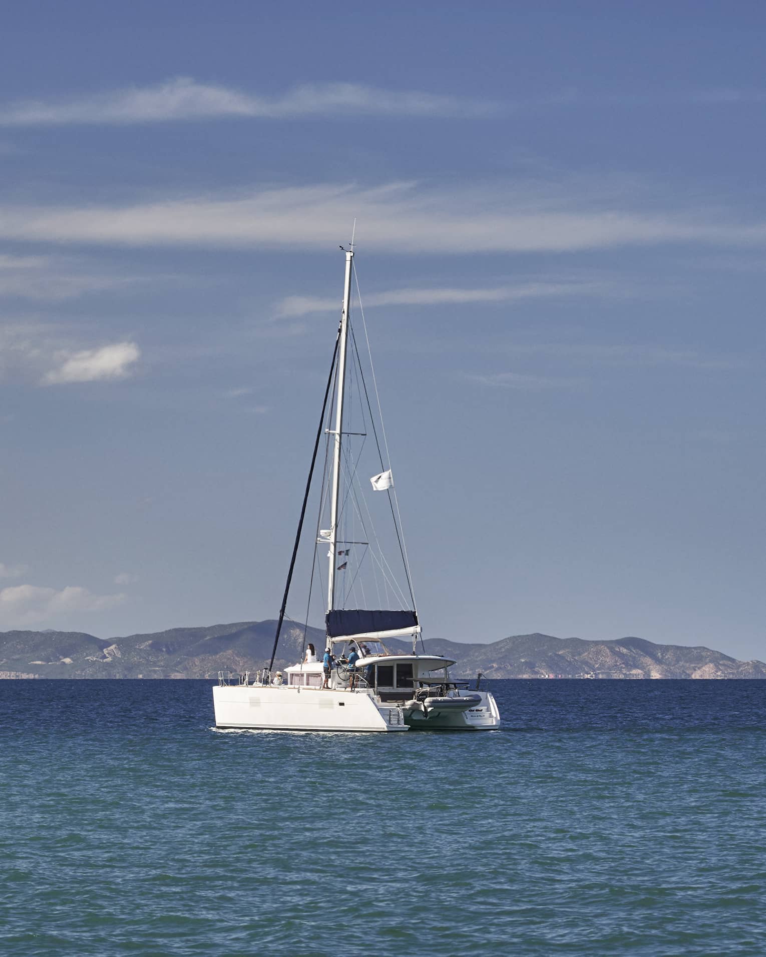A boat sailing on the ocean with mountains in the distance.