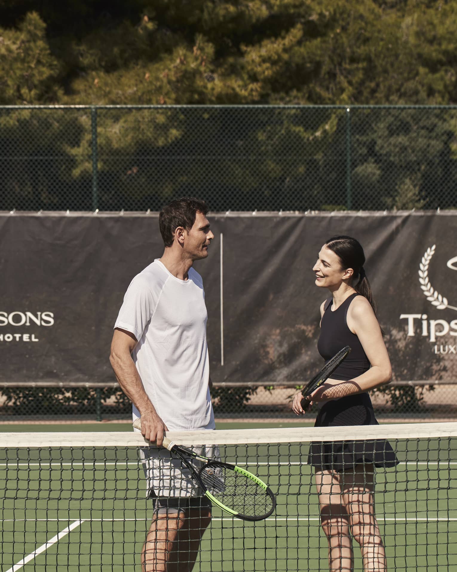 A man and woman holding tennis rackets on a court.