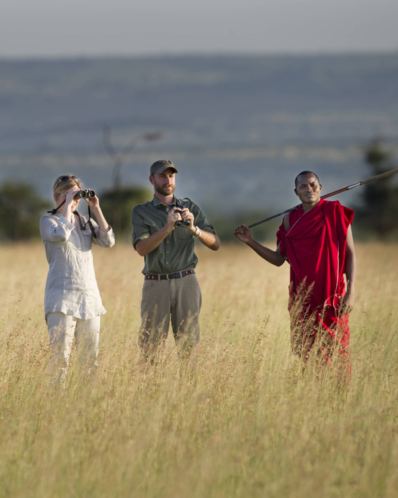 Couple takes photos on walking safari through tall grass with guides