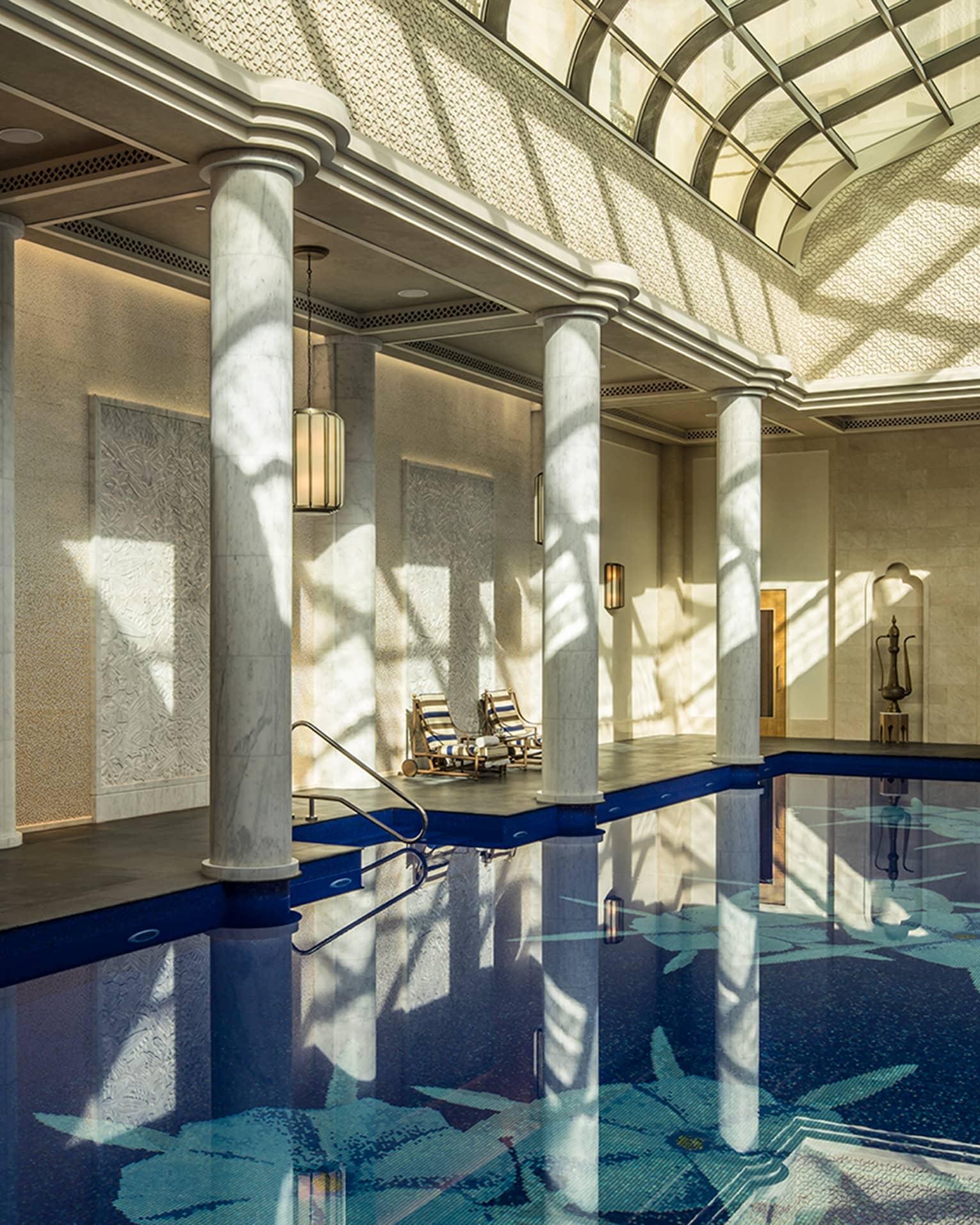 Long indoor swimming pool under curved skylights and tall white pillar columns