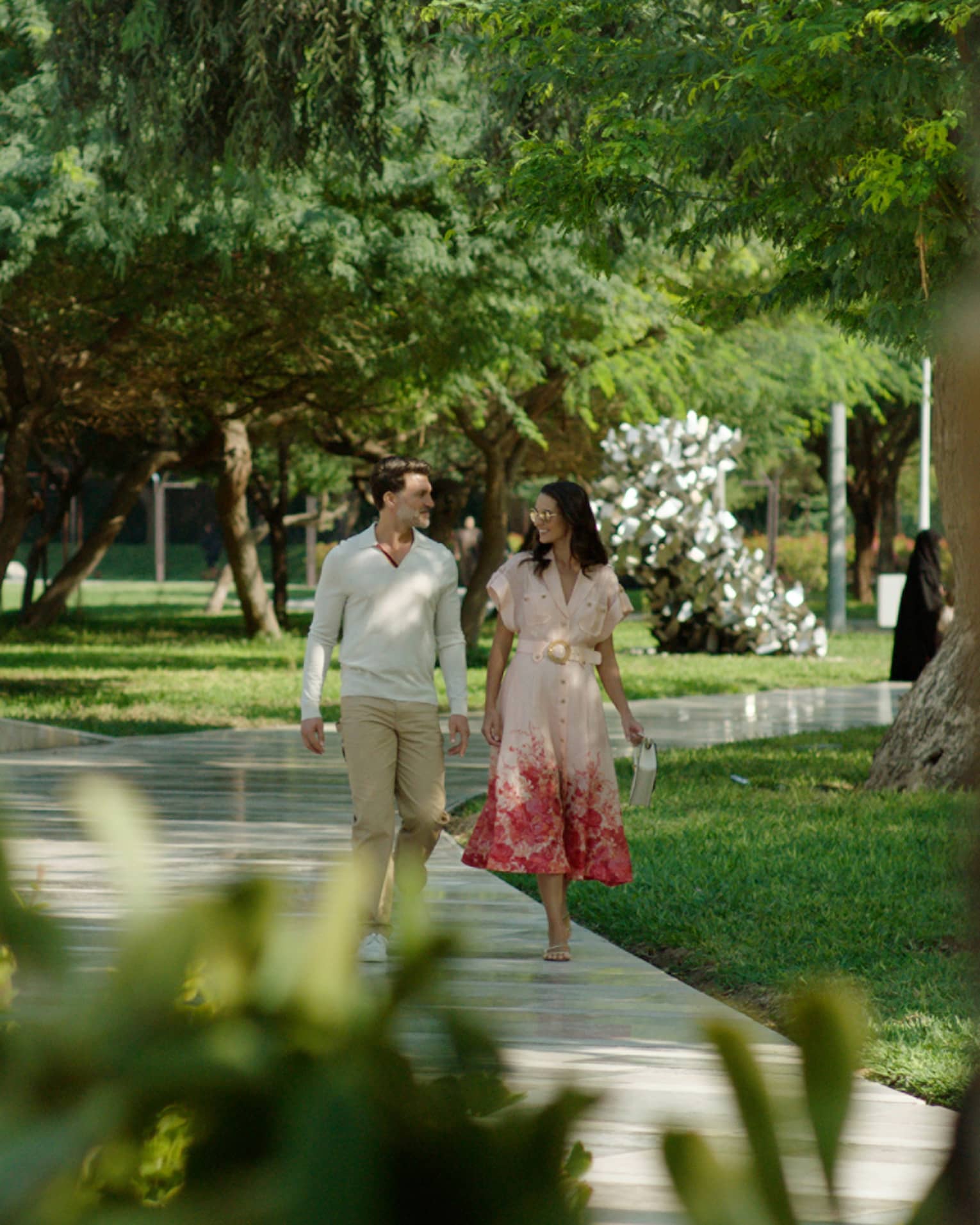 Couple walks along pathway surrounded by flora and fauna