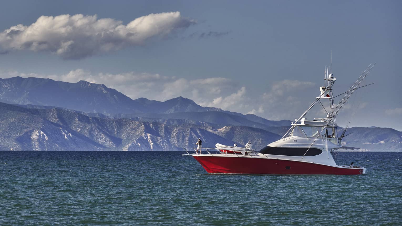 A white and red boat on the water with mountains in the distance.
