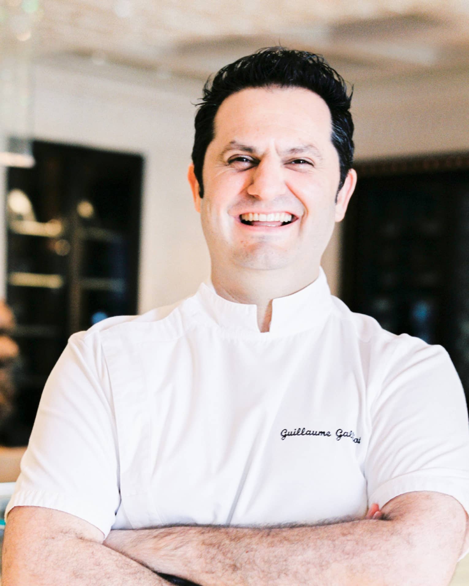 Portrait photo of Chef Guillaume Galliot in uniform and crossing arms