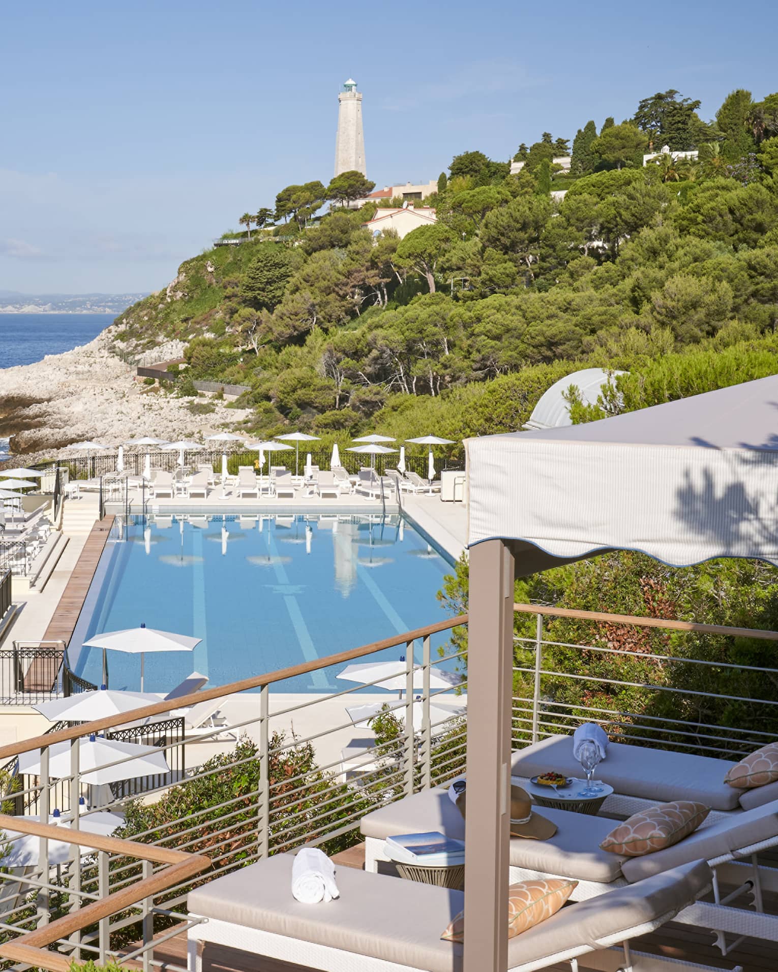 View from terrace of Club Dauphin pool, Mediterranean, green hillside and lighthouse