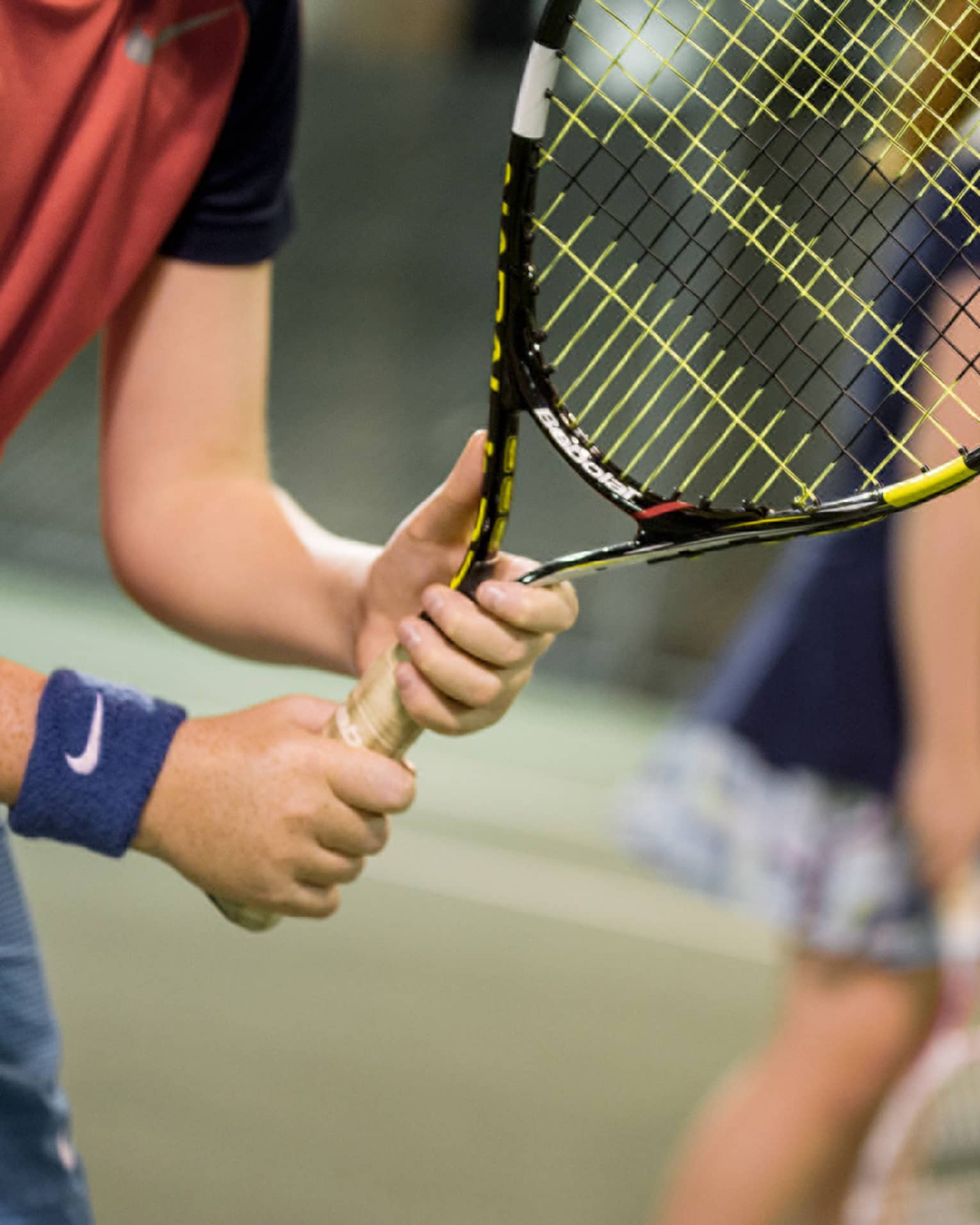 Close-up of hands holding yellow-and-black tennis racket