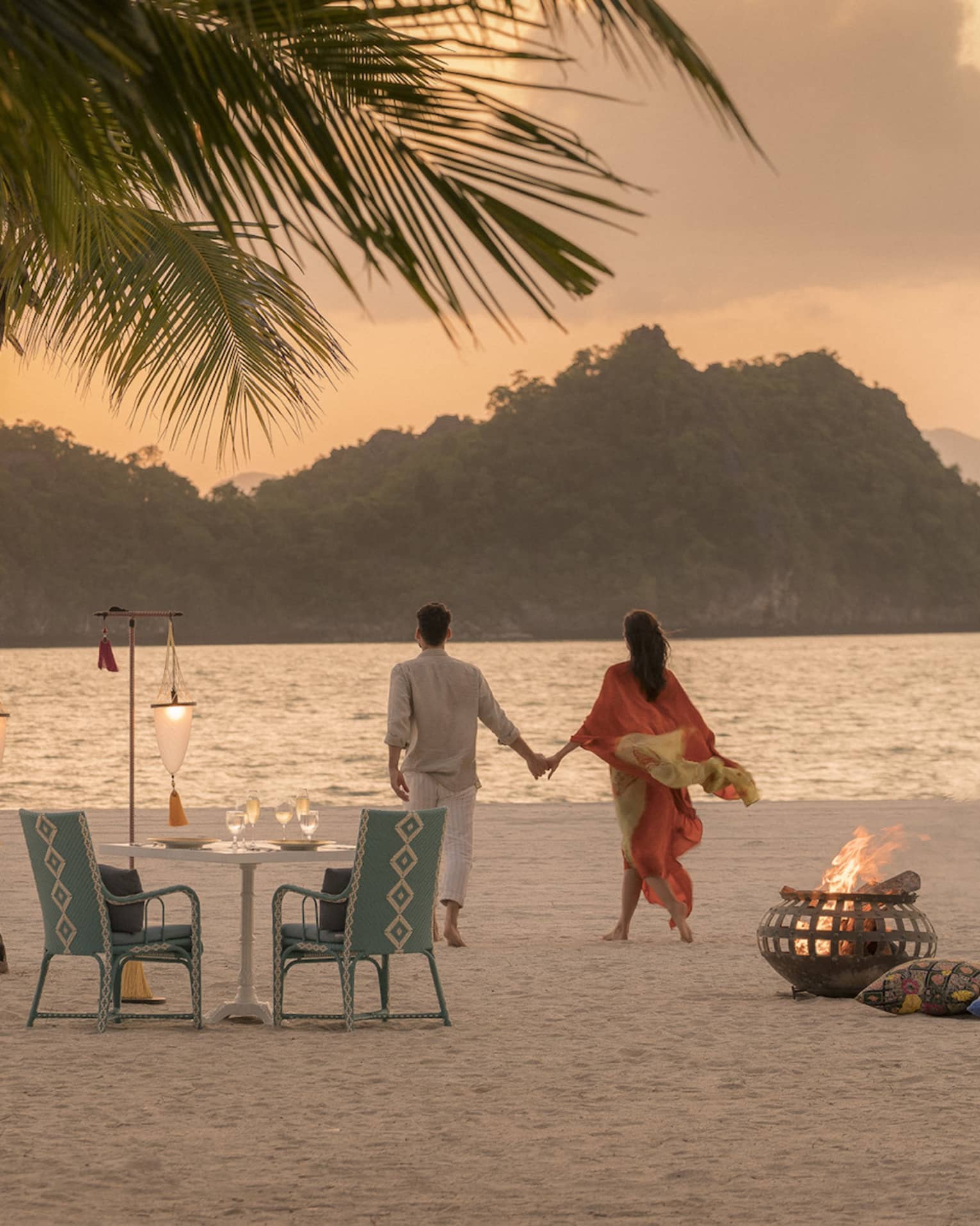 A man and woman on a beach having a Punta chintai private dinner at Four Seasons Langkawi