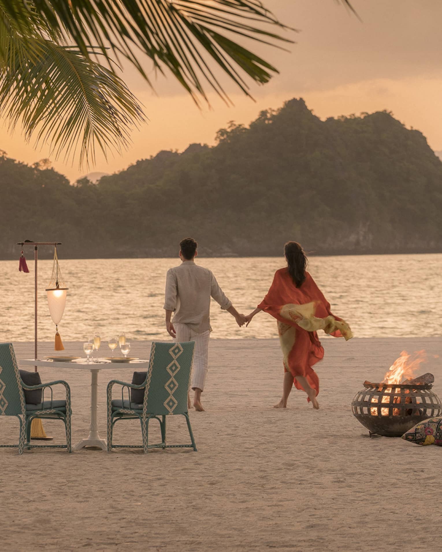 A man and woman on a beach having a Punta chintai private dinner at Four Seasons Langkawi