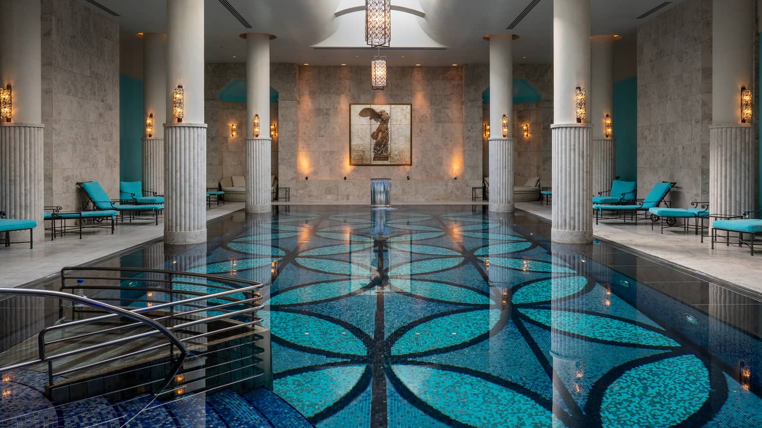 Indoor pool with blue-patterned floor, white up-lit columns and skylight
