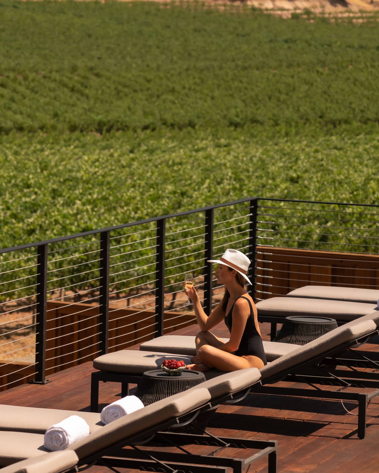 Woman on sun lounger, overlooking wine vineyards