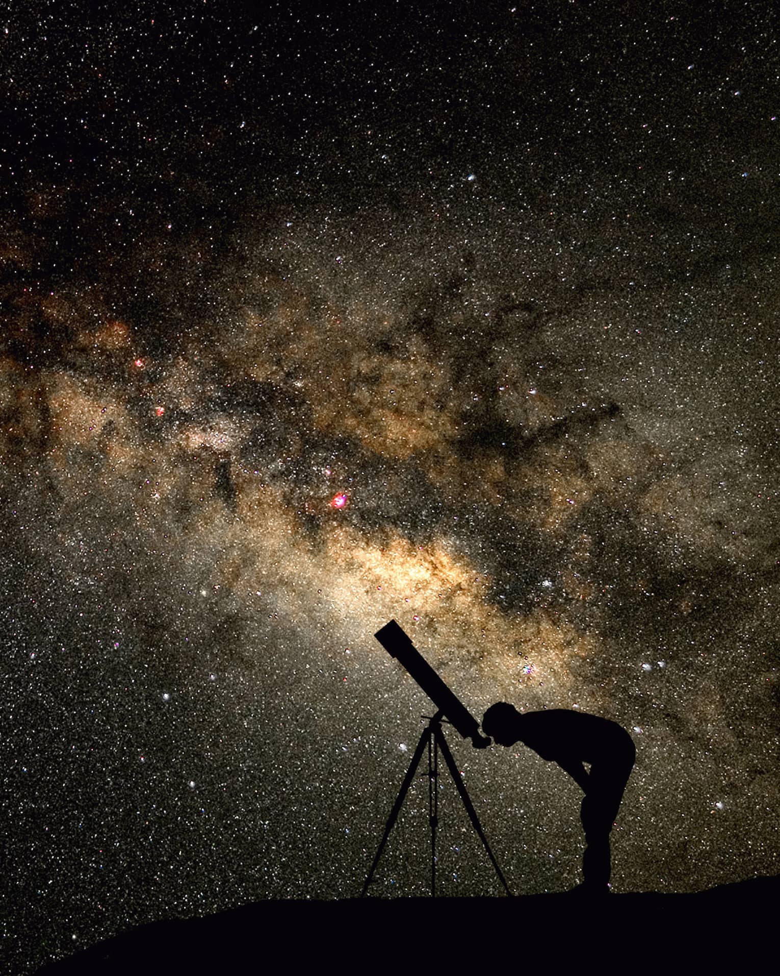 Silhouette of stargazer leaning into telescope against a starry sky, milky way