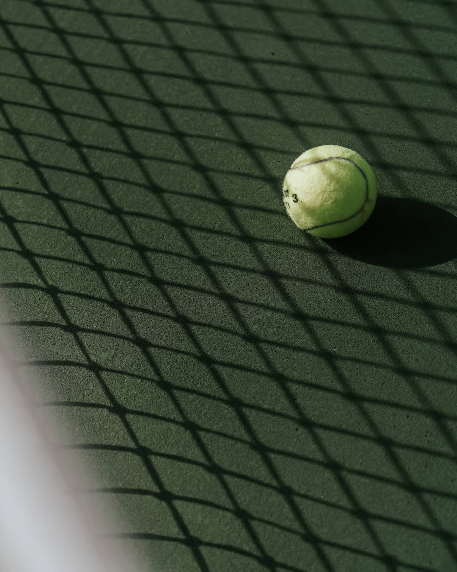 Tennis ball on tennis court with shadow of net