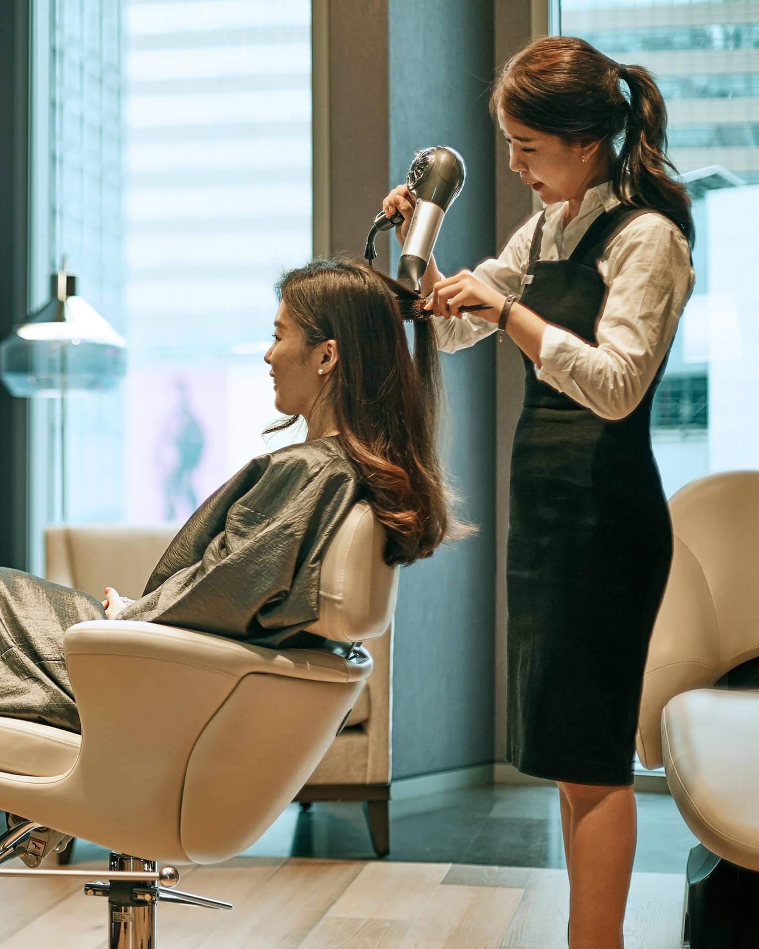 Hair stylist blow dries woman's hair in hotel salon