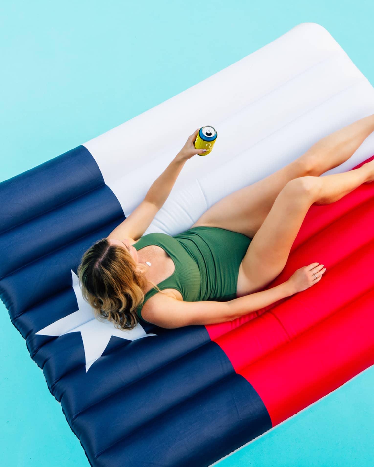 a woman lounges in a pool on a float that looks like the texas state flag