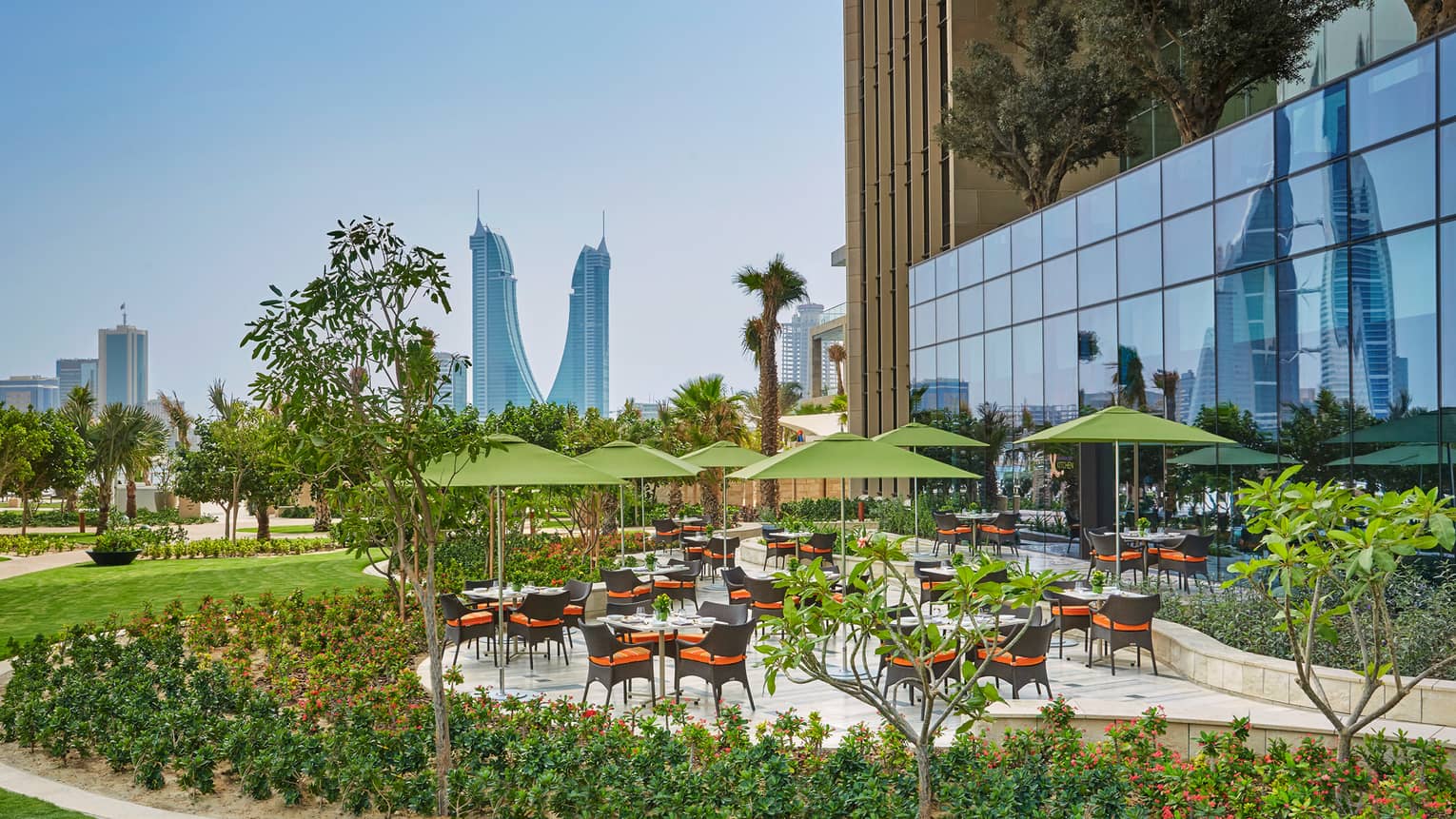 Bahrain Bay Kitchen outdoor patio tables, umbrellas, surrounded by green gardens, lawn