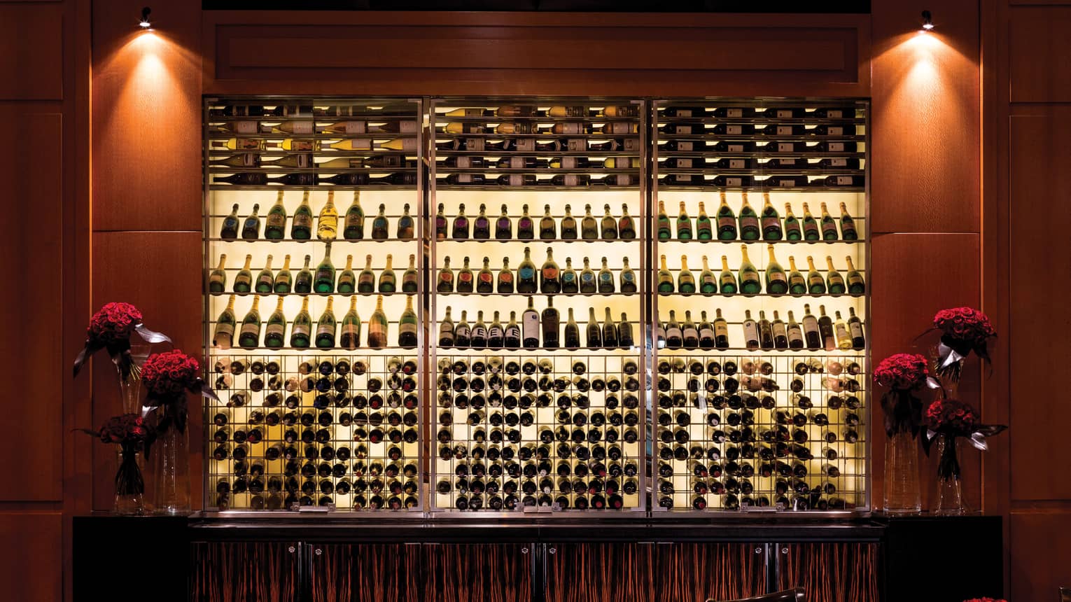 Illuminated wine bottle racks on wood wall in restaurant lounge