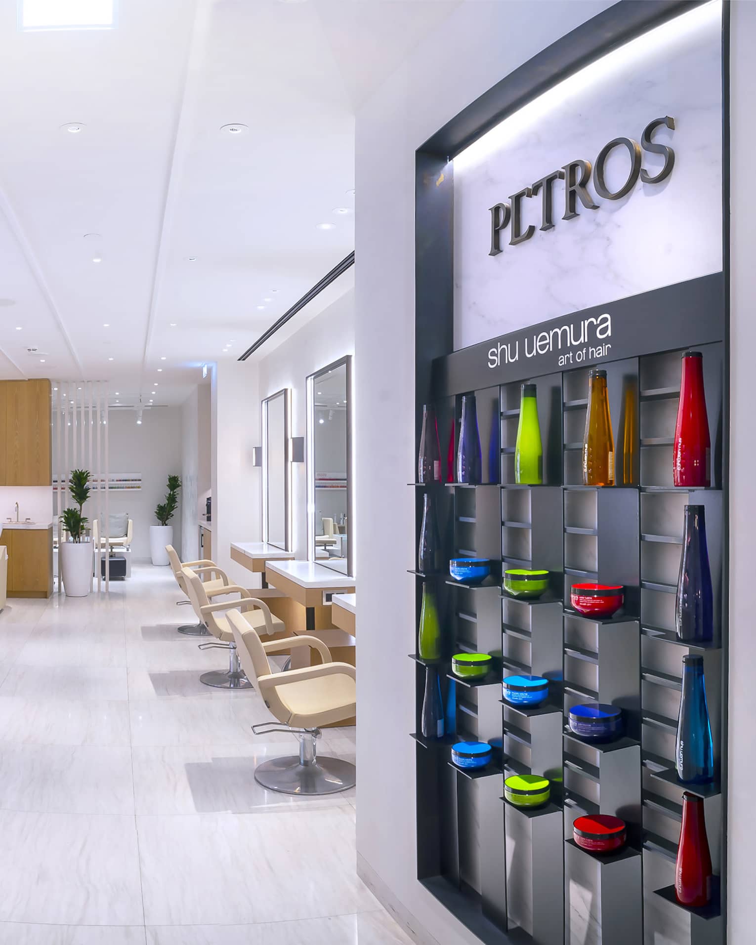 Petros Hair Salon reception desk with hair products on wall and view into salon