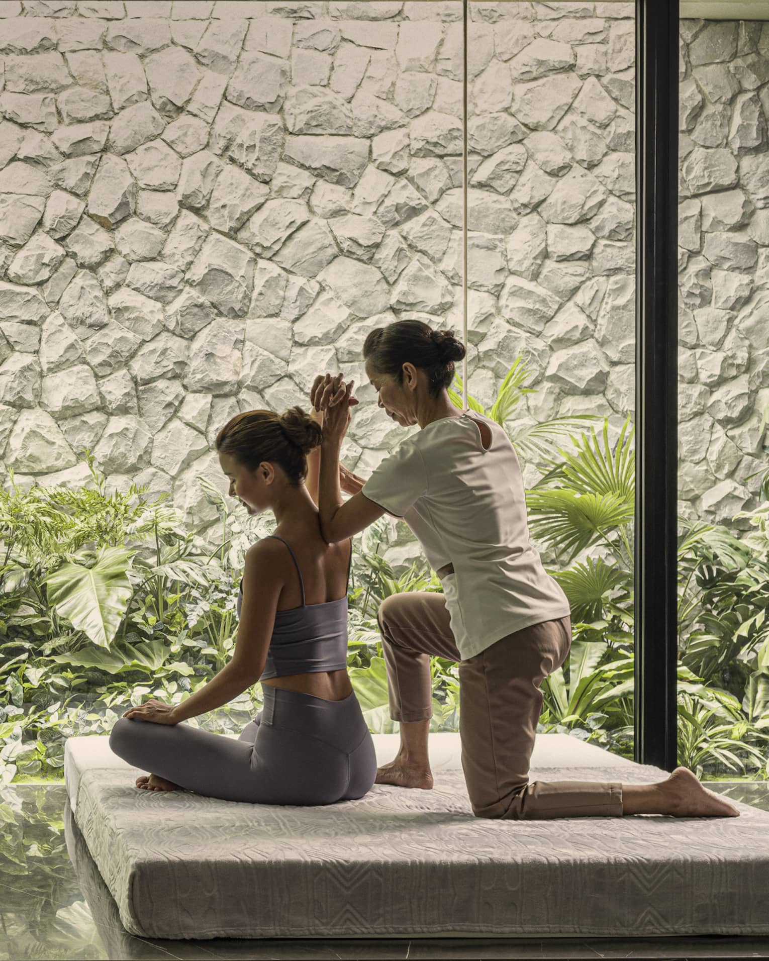 Massage therapist performs a traditional Thai massage on female guest