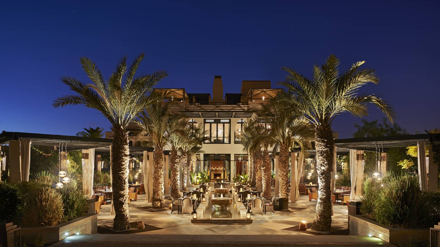 Bleu d'Orange large outdoor patio with lights and palm trees under night sky