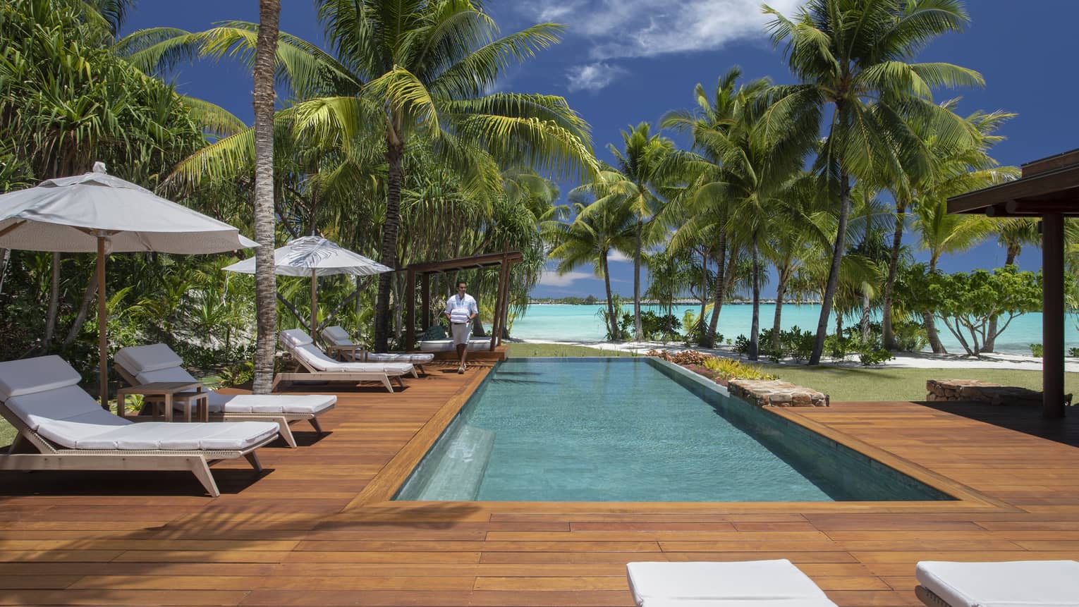 Villa's private pool with a lagoon view, surrounded by a wooden deck with sun chairs