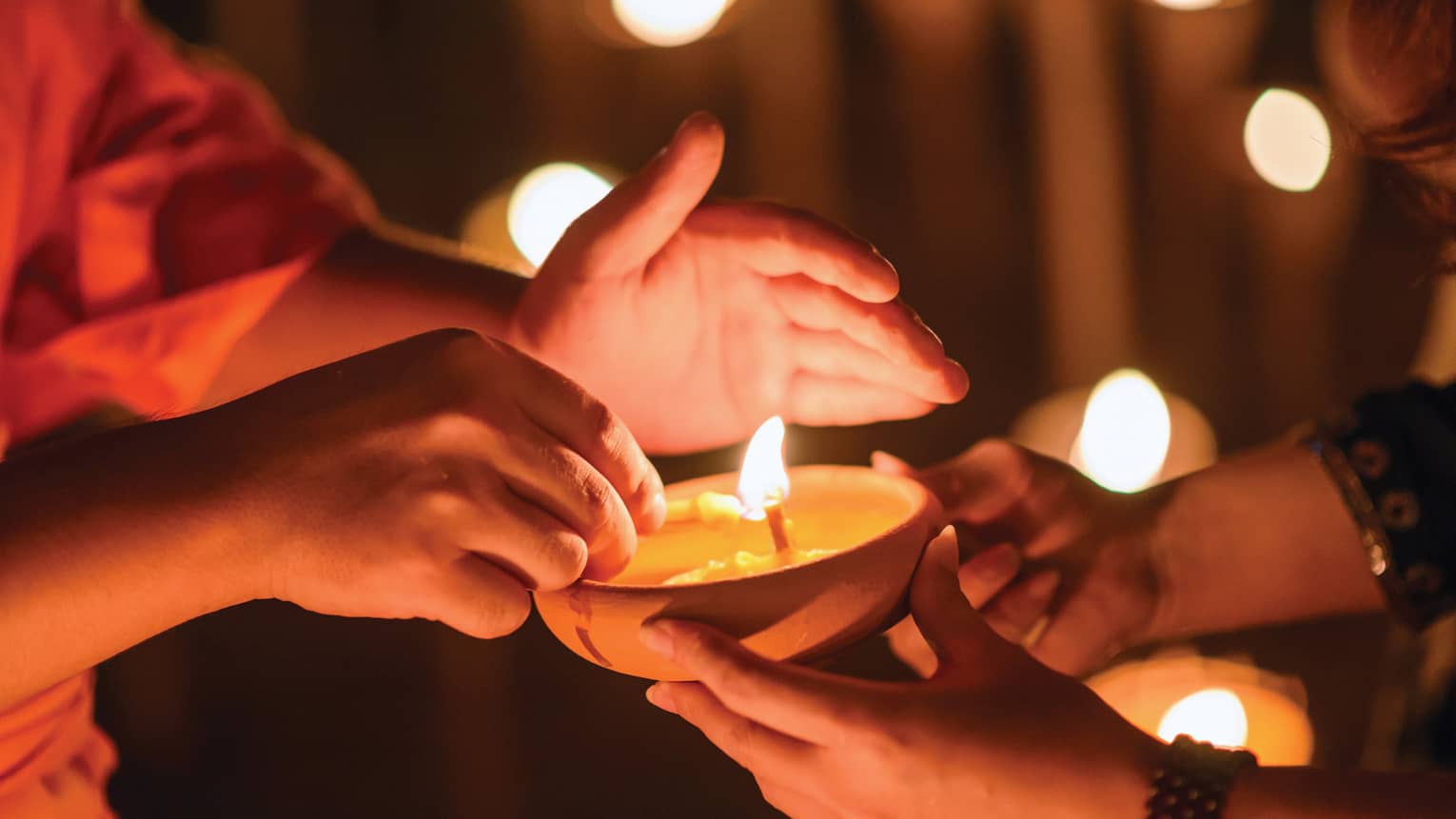 Buddhist monk hands holding candle cup in dark