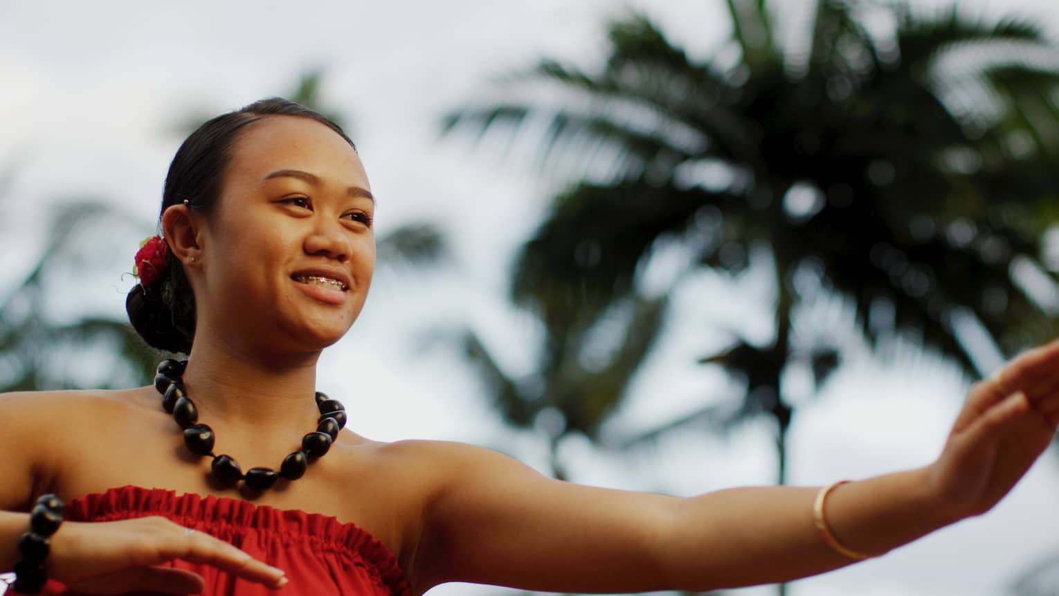 Close up of smiling Polynesian woman dancing under palm tree