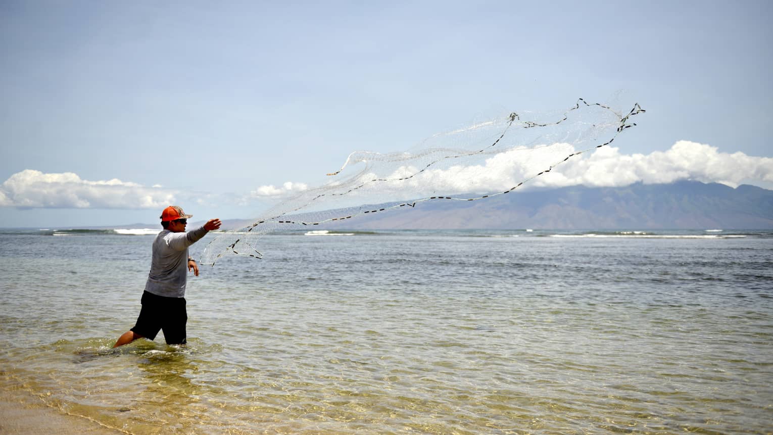 Man throws Hawaiian fishing net across lagoon