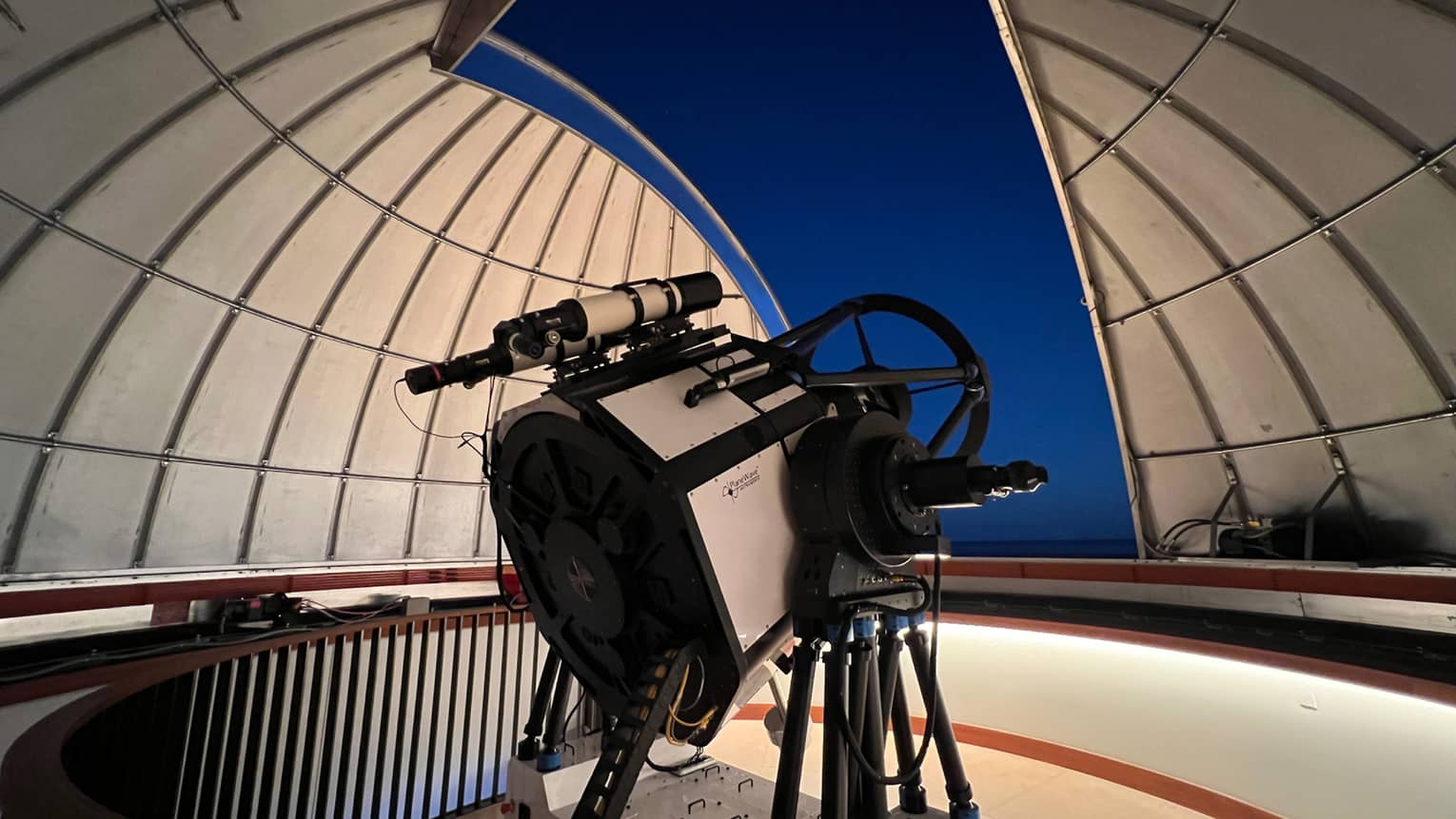 Large telescope from the Lanai Observatory peering out of a dome into the night sky