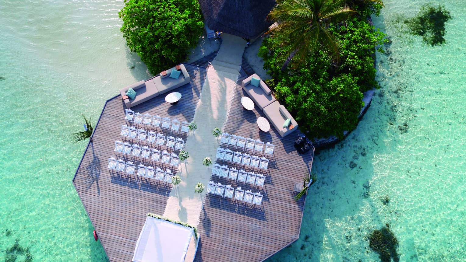 Aerial view of wedding ceremony, rows of white chairs on dock over lagoon