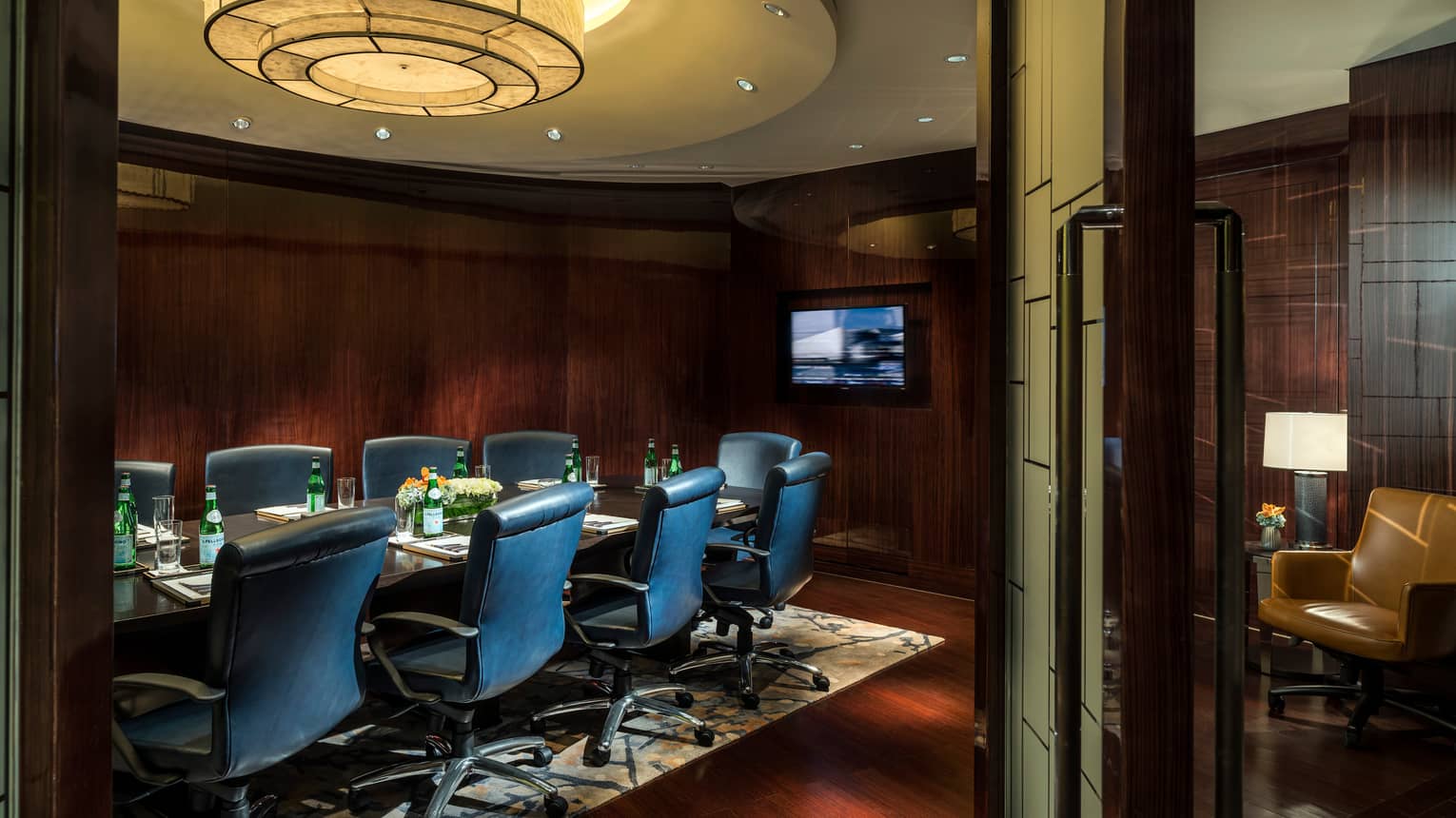 Business Centre meeting table with tall leather chairs, TV screen