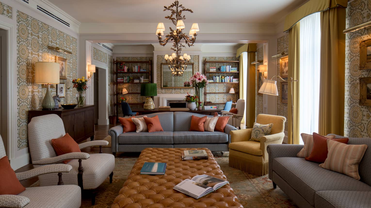Royal Suite sofas, chairs around long tufted leather bench under chandeliers, bookshelves