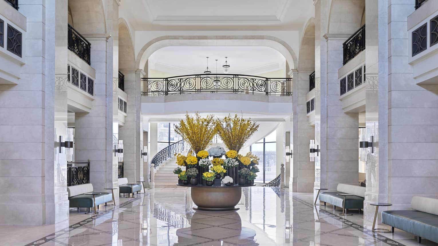 The all-white marble lobby with a large yellow flower display in the centre. 