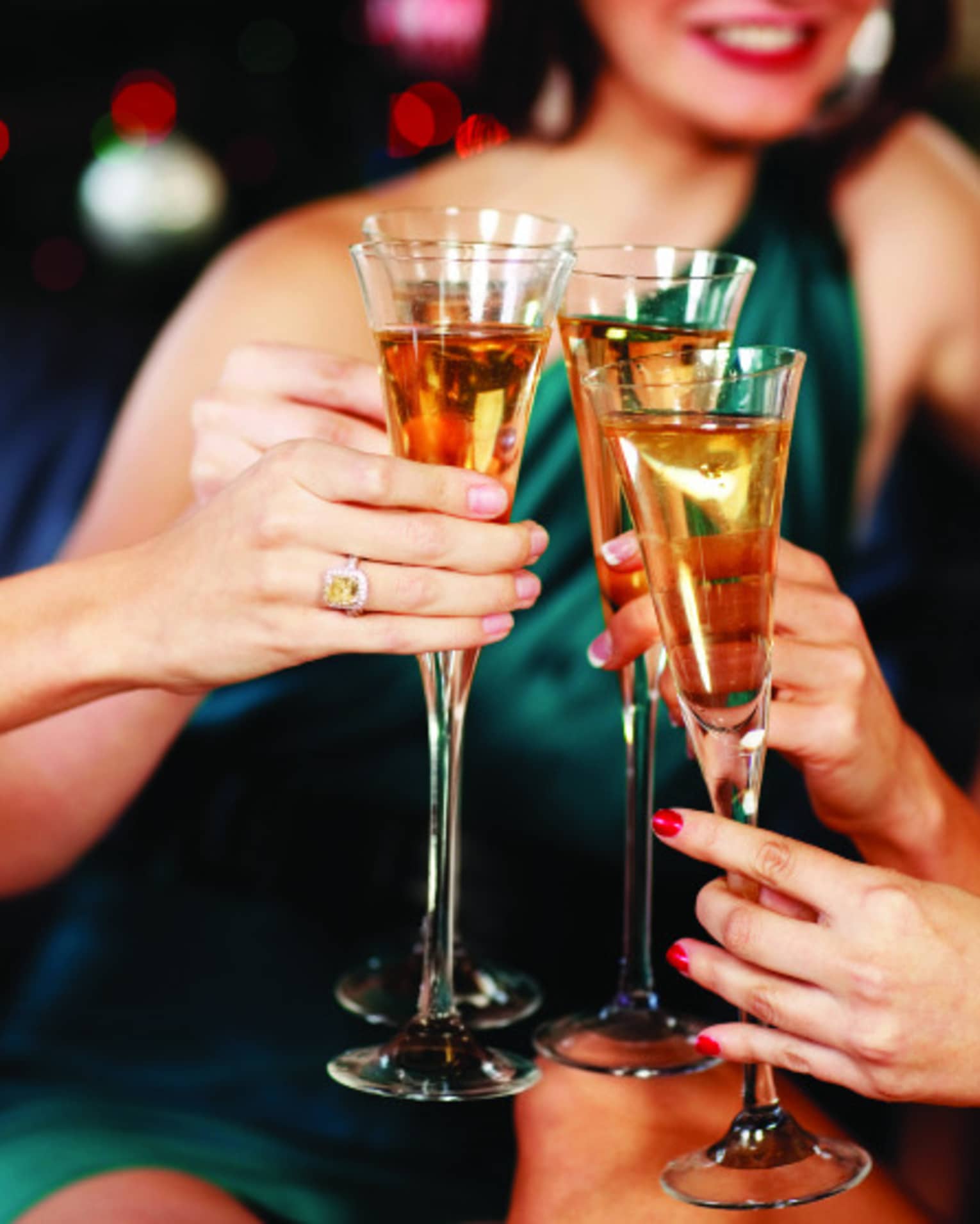 Close-up of women in evening gowns toasting with glasses of Champagne