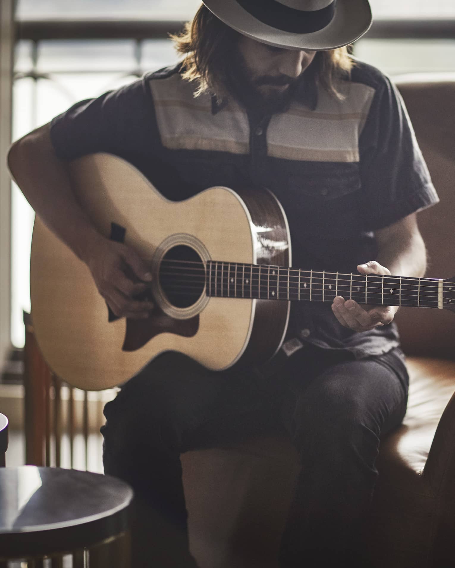 Guitar Concierge plays Taylor acoustic guitar on modern armchair