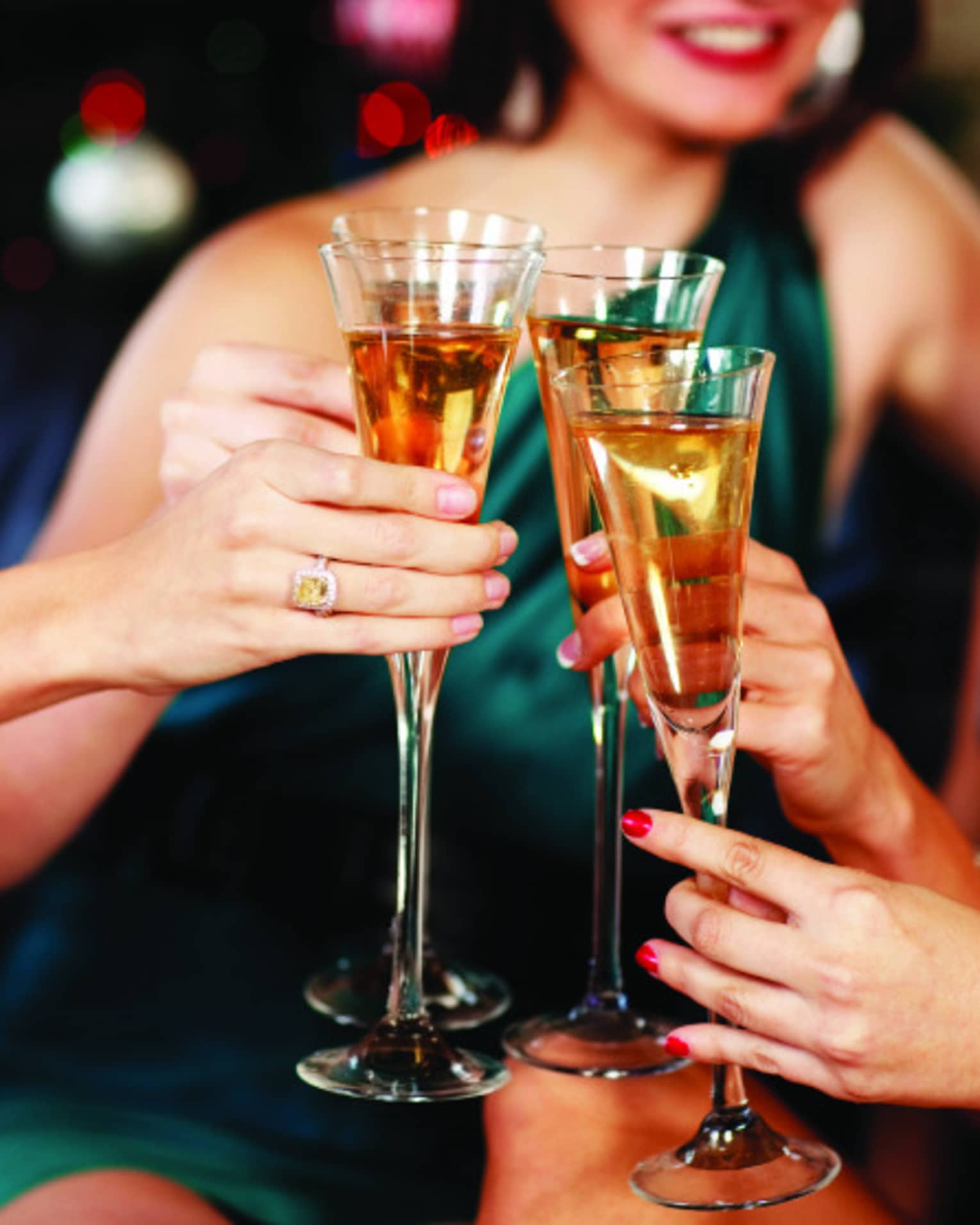 Close-up of women in evening gowns toasting with glasses of Champagne