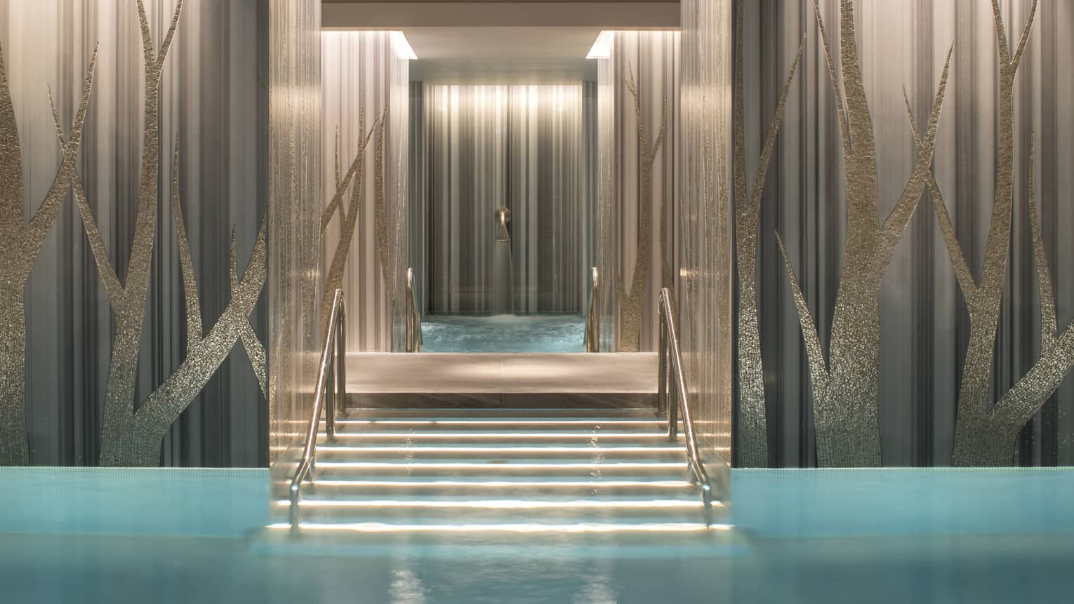 Stairs to blue spa pool with up-lit metallic tree pattern–embossed walls