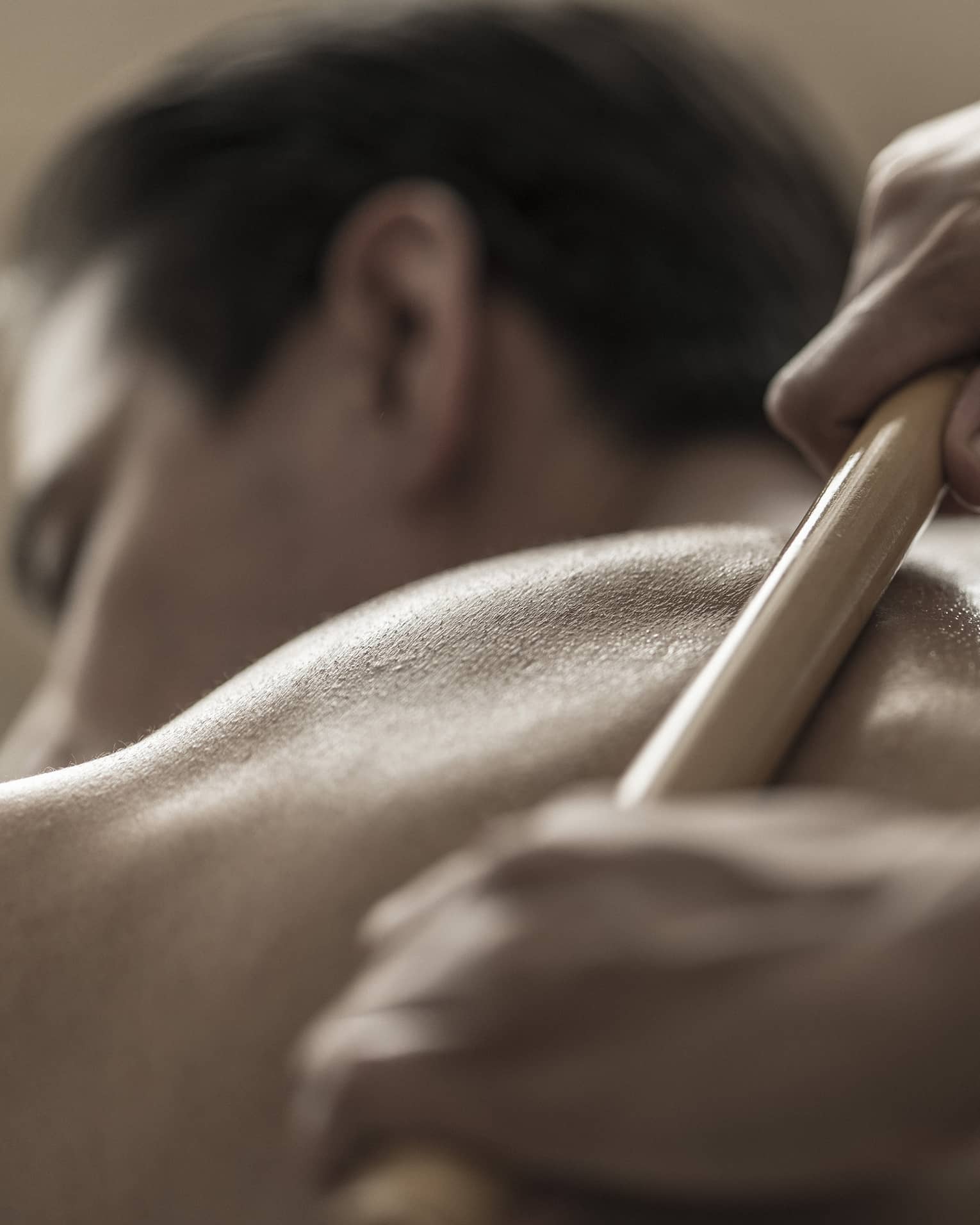 A spa attendant uses a tool to massage a guest's back