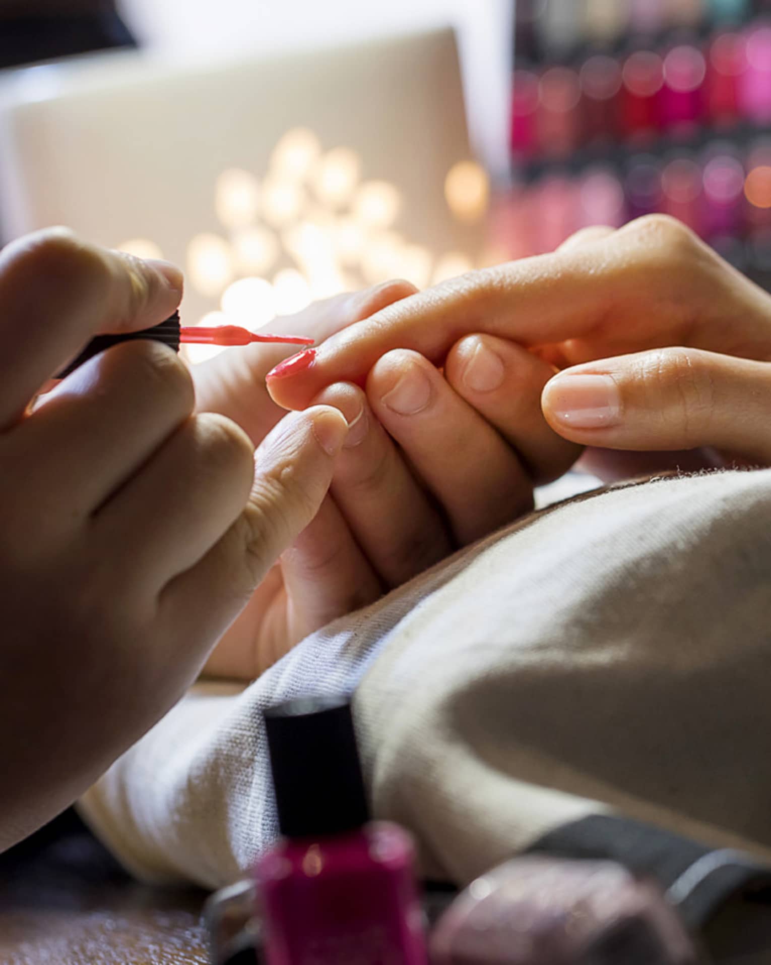 Close-up of manicure, hands resting on pillow as nails painted