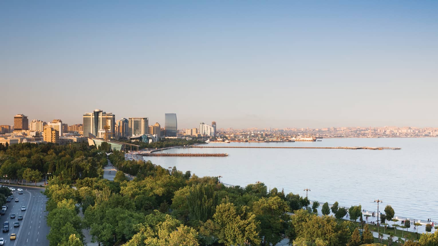 Aerial view of Baku skyline during the day with canopy of trees, high rise buildings, Caspian Sea