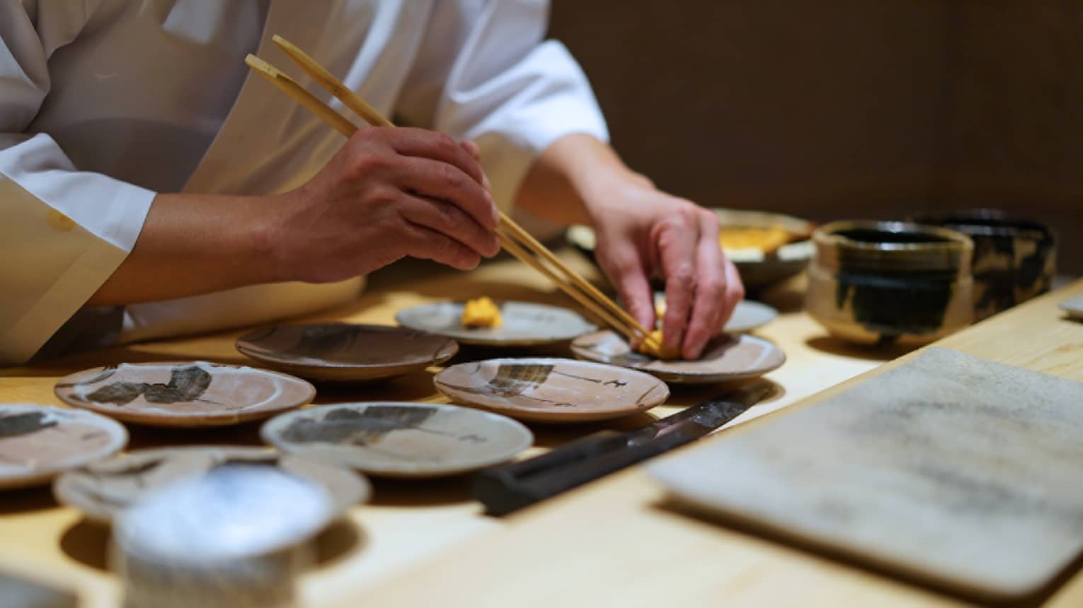 Close up of a chef using chopsticks to place a Food detail on a ceramic plate