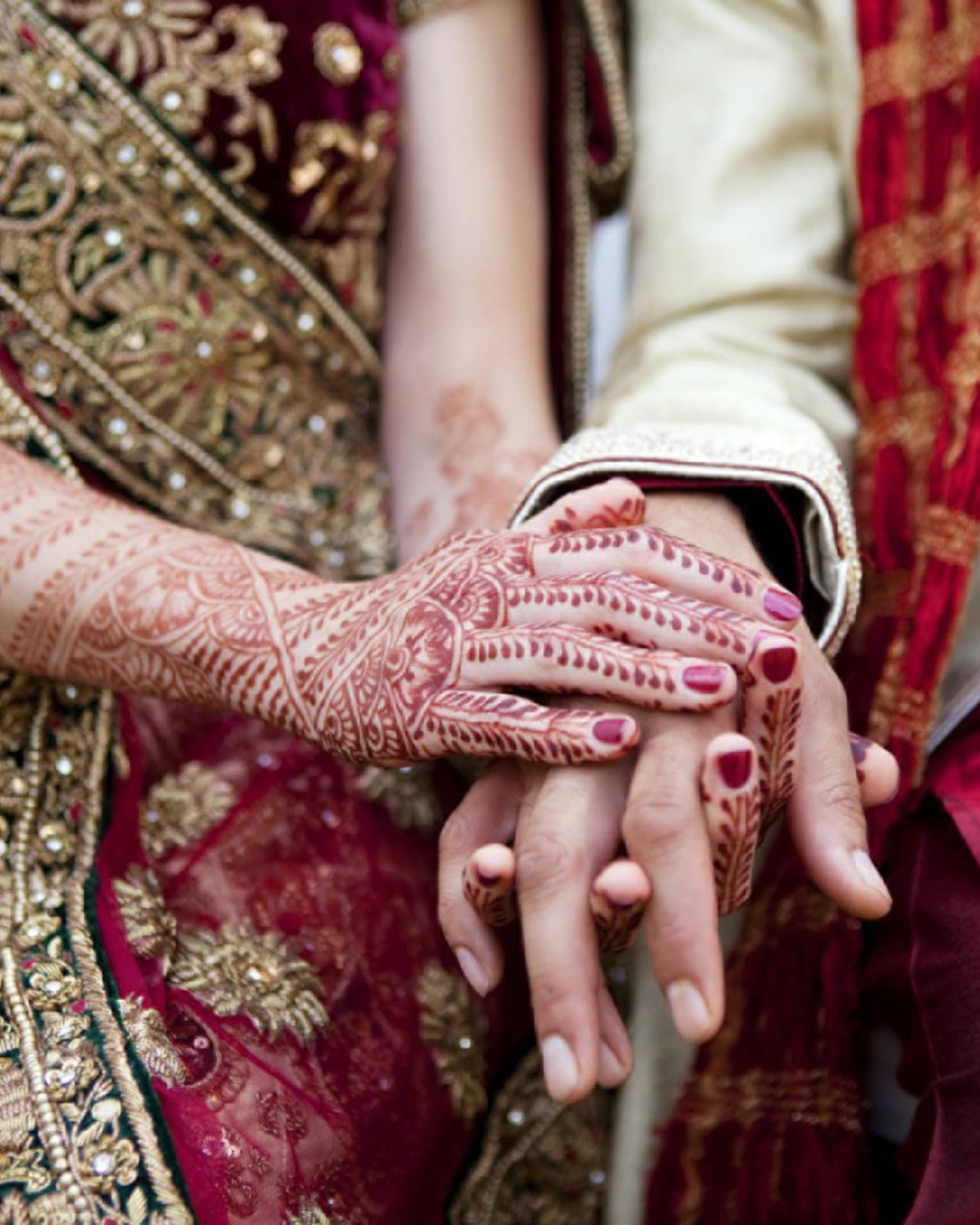 Indian wedding ceremony, bride with henna designs on arm holds groom's hands