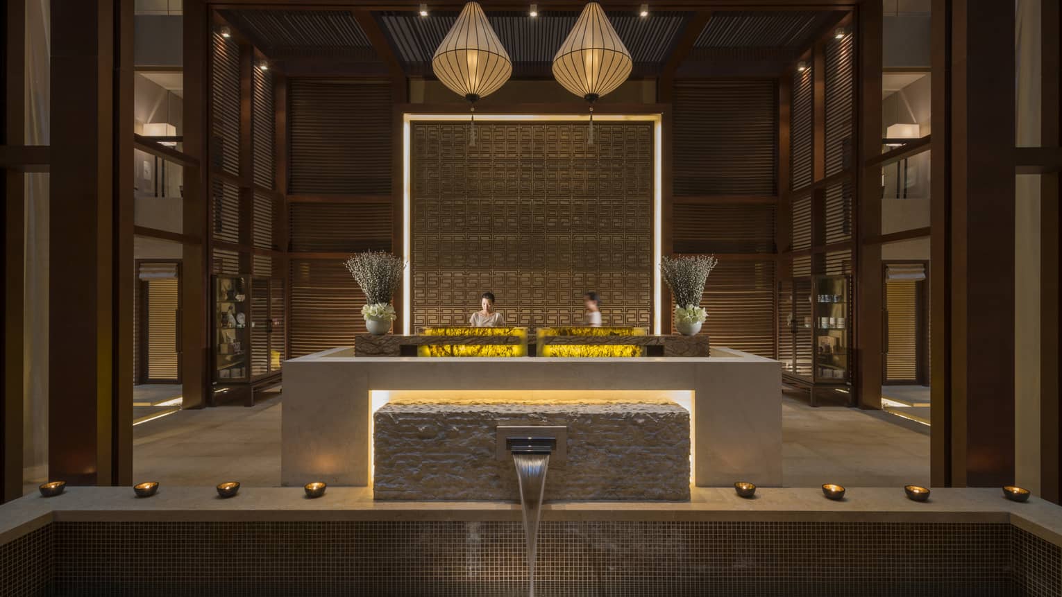 Water pours from fountain into tile pool in front of hotel spa lobby desk