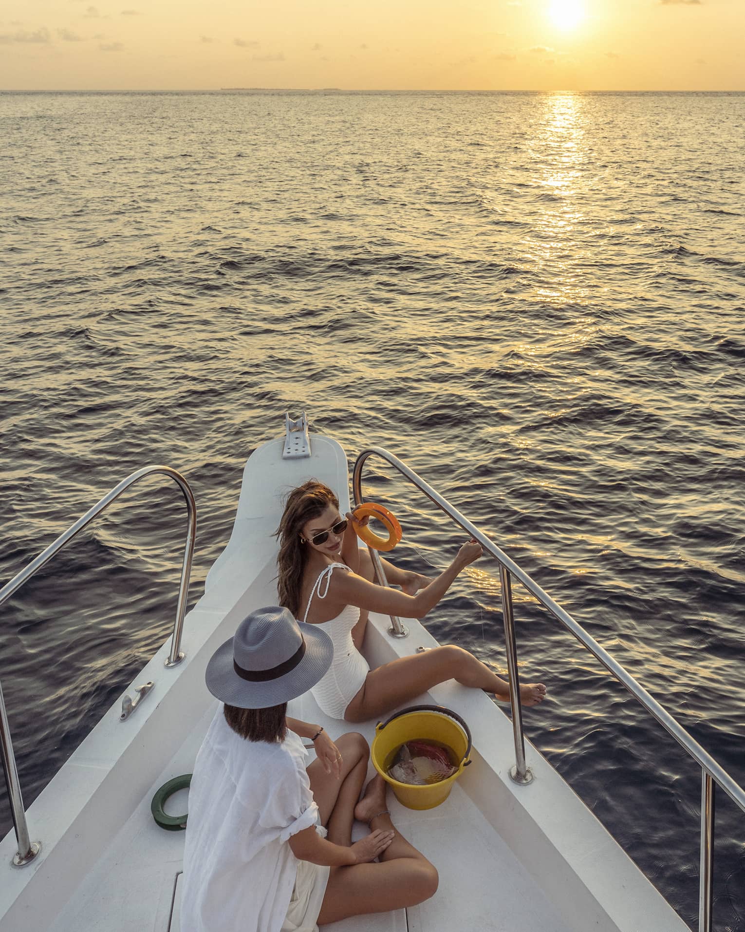 Two women enjoy snacks at the helm of a private yacht at sunset