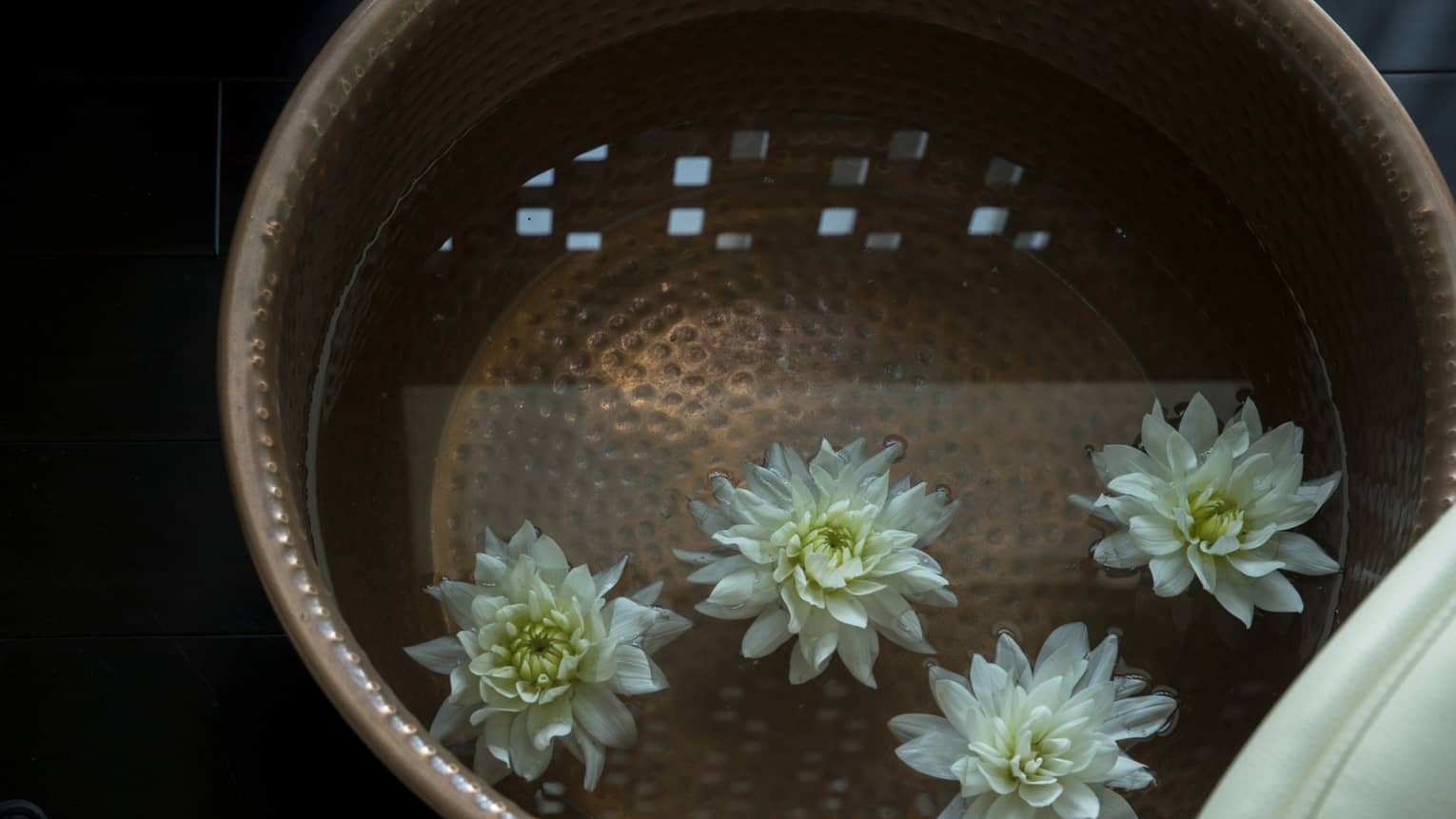 Close-up of fresh white flowers floating in water in copper bowls