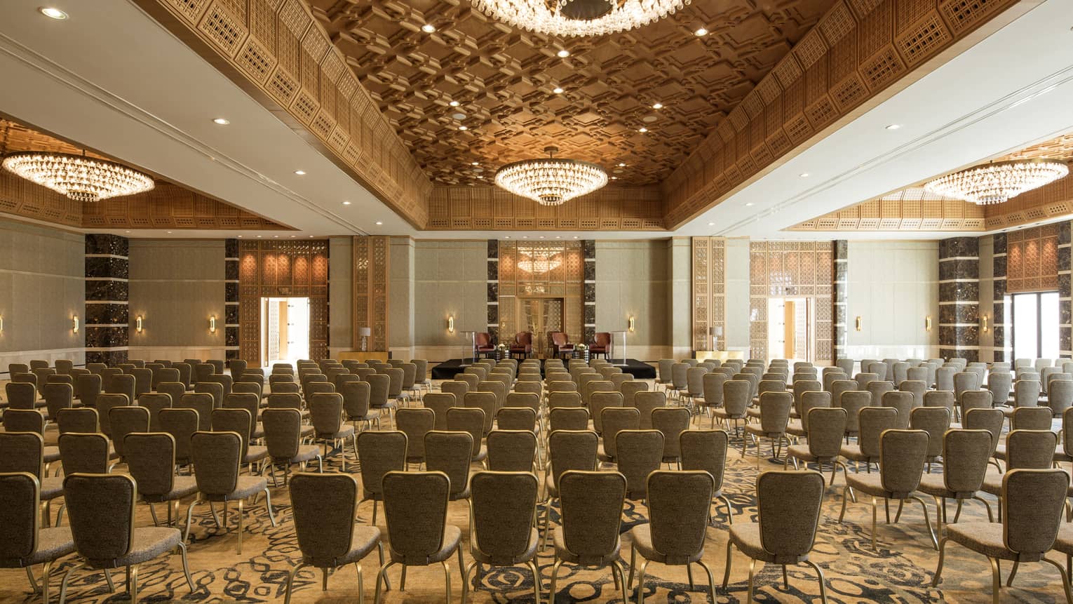 Chairs arranged in rows in Jasmin Ballroom accented with gold and large chandeliers 