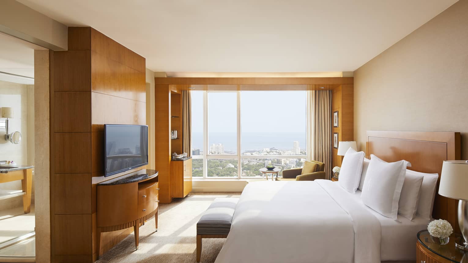 Deluxe room with natural light coming in and a view of the Mumbai skyline