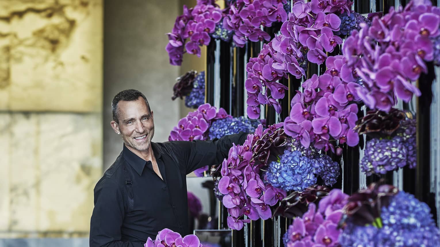 Florist arranges purple and blue flowers in tall black vases