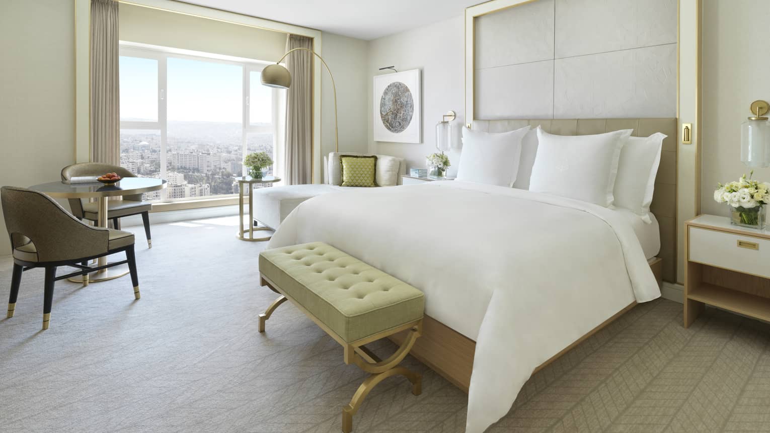 A spacious suite with a large bed in the centre of the room. Opens to a floor-to-ceiling window overlooking Amman.