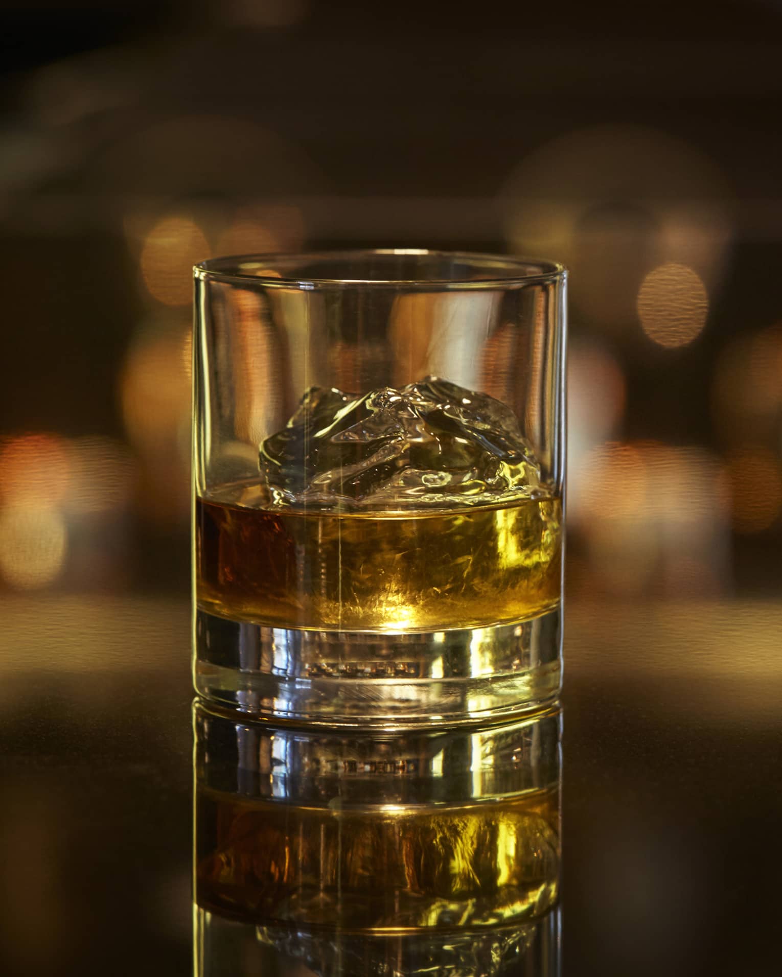 Scotch on the rocks, liquor on ice cubes in rock glass on bar 