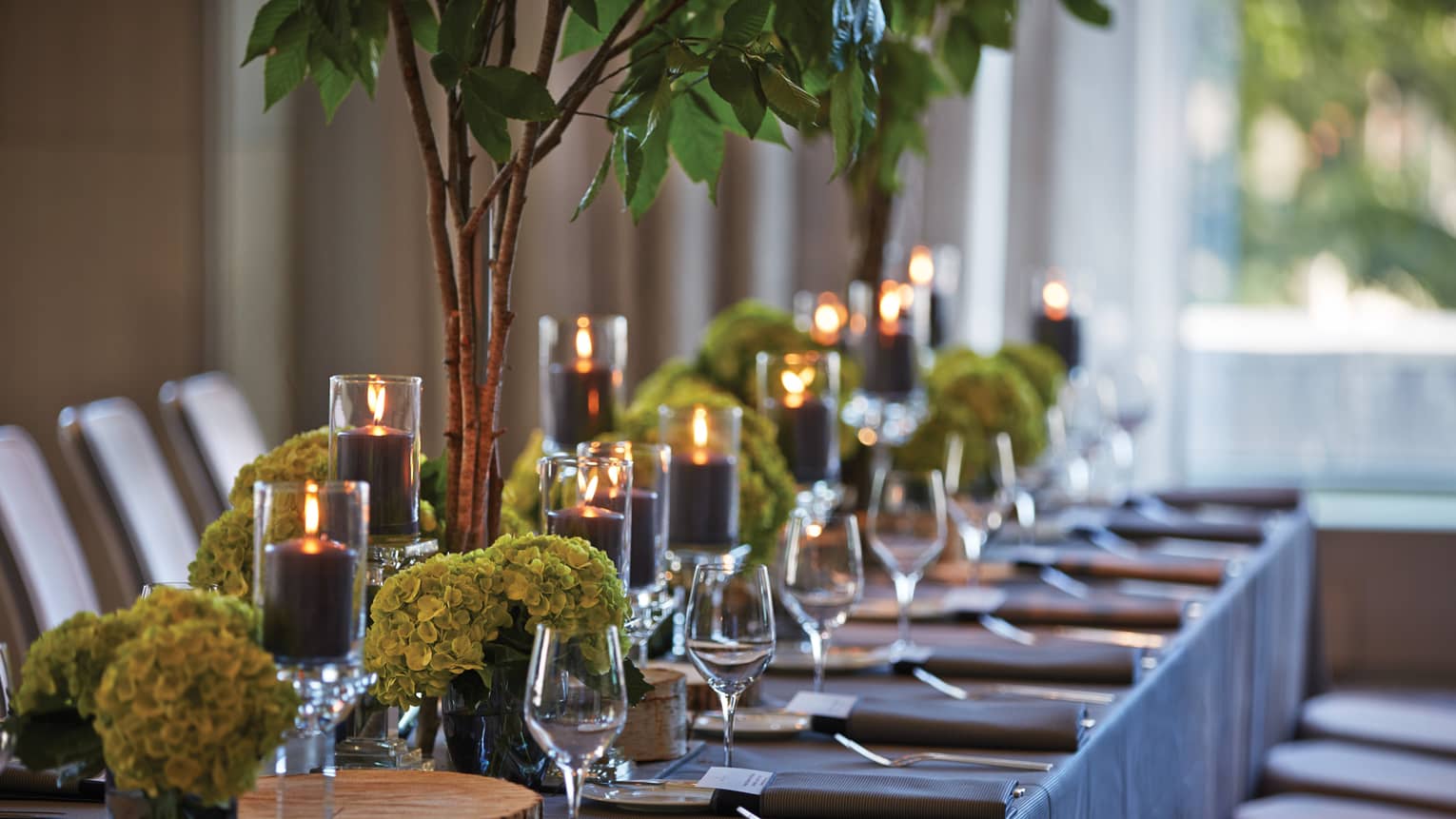 Black pillar candles in votives, green flowers, wine glasses along banquet table